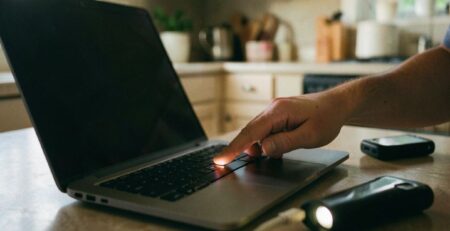 Πάτημα κουμπιού λειτουργίας σε laptop με μαύρη οθόνη και συνδεδεμένο φορτιστή