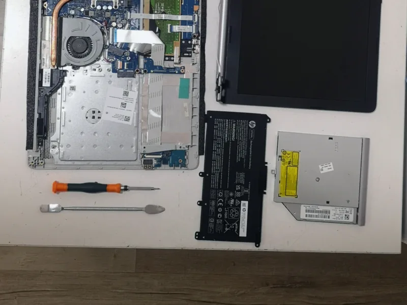 Laptop αποσυναρμολογημένο στον πάγκο, με τη μπαταρία και τον δίσκο δίπλα