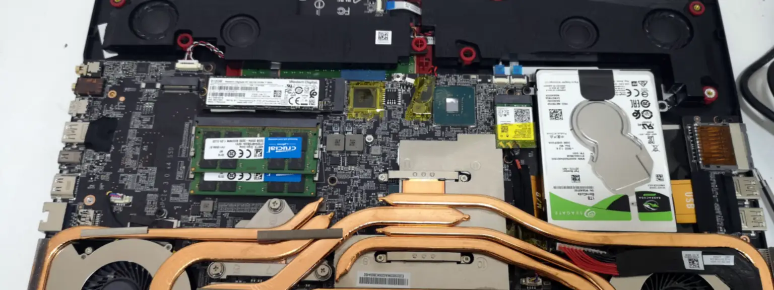 Ανοιχτό laptop στον πάγκο, με χαλκοσωλήνες ψύξης, μνήμη RAM, SSD και σκληρό δίσκο