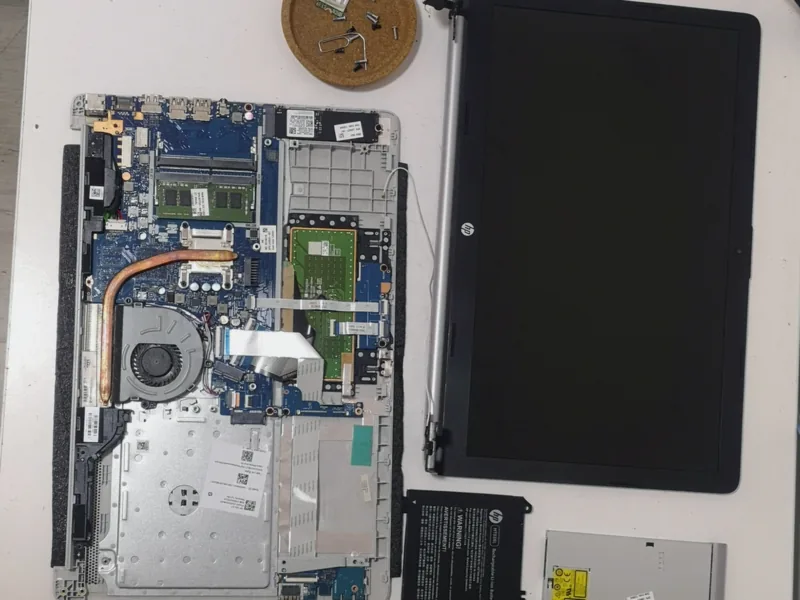 Laptop αποσυναρμολογημένο στον πάγκο, με την οθόνη, τη μπαταρία και τον δίσκο δίπλα